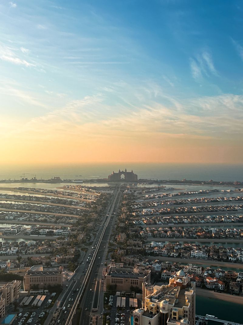 Aerial view of Palm Jumeirah at sunset, with a resort hotel at the end of the central road