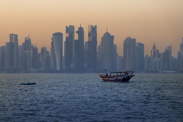 Doha’s skyline at sunset with a traditional dhow on the water