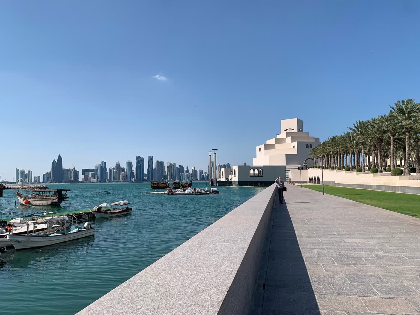 Doha’s skyline across the water from the Corniche, with dhows moored and the Museum of Islamic Art at right