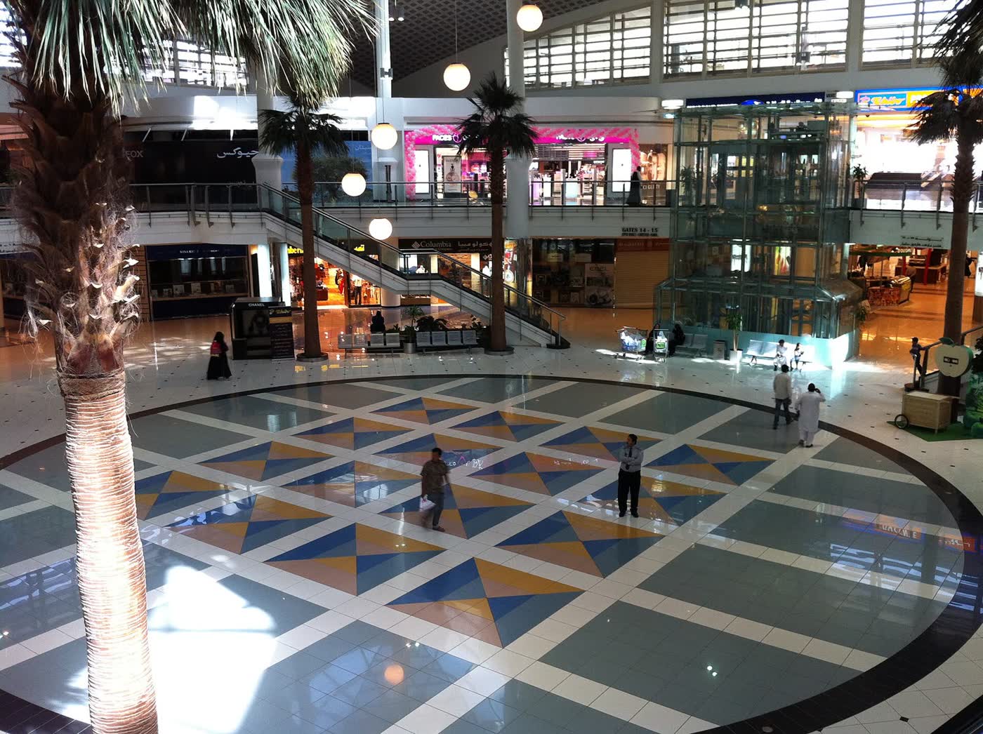 The atrium of a shopping mall in Riyadh, with palm trees and a tiled floor in a geometric pattern