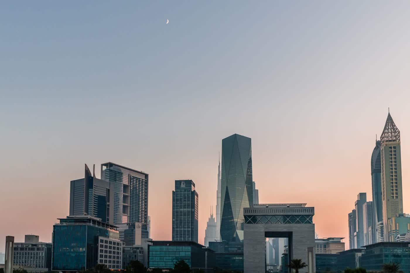 The skyline of Dubai’s financial district at sunset, with the stone Gate building and glass towers