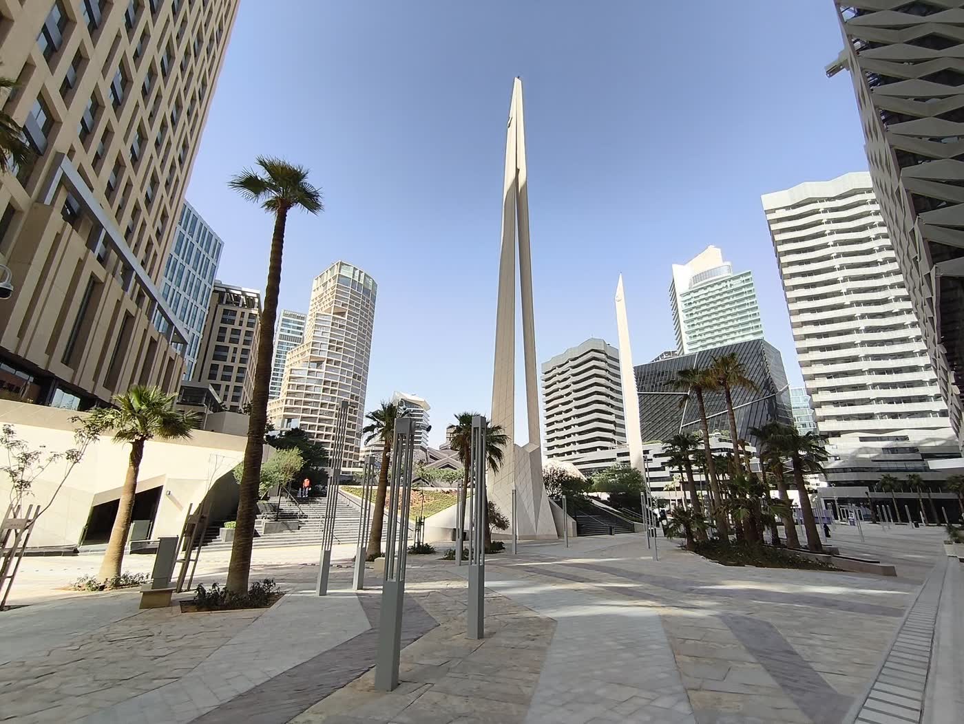 A pedestrian plaza between modern towers and palm trees in the King Abdullah Financial District in Riyadh
