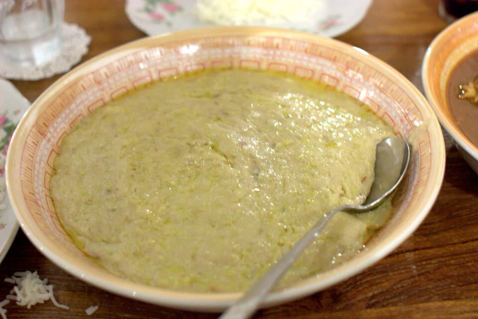 A wide bowl of pale, smooth porridge with a spoon resting in it