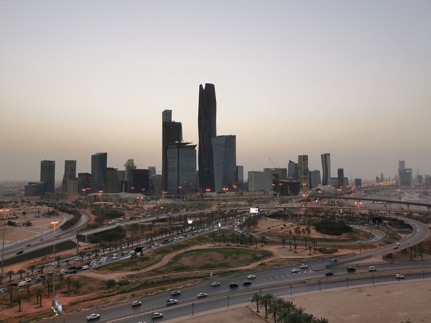 The skyline of the King Abdullah Financial District in Riyadh at dusk, with a road interchange in the foreground